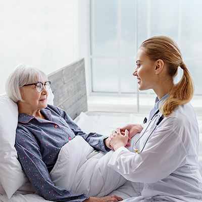 Nurse speaking with elderly woman in bed