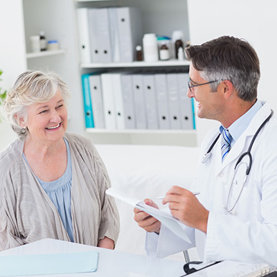 elderly woman smiling and speaking with a doctor