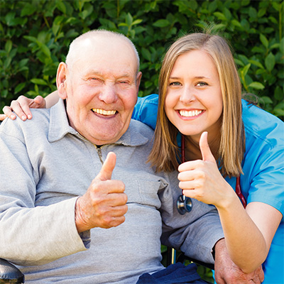 elderly man and nurse smiling and giving a thumbs up