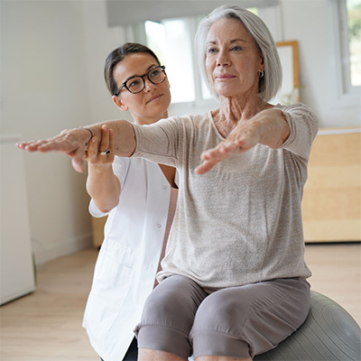 rehab nurse assisting elderly woman with an exercise